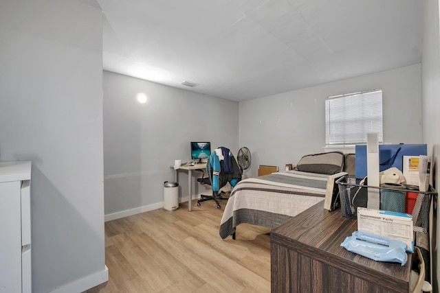 bedroom with light wood finished floors, visible vents, and baseboards