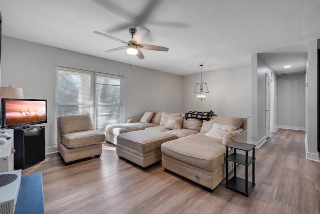 living area featuring light wood-type flooring, baseboards, and a ceiling fan