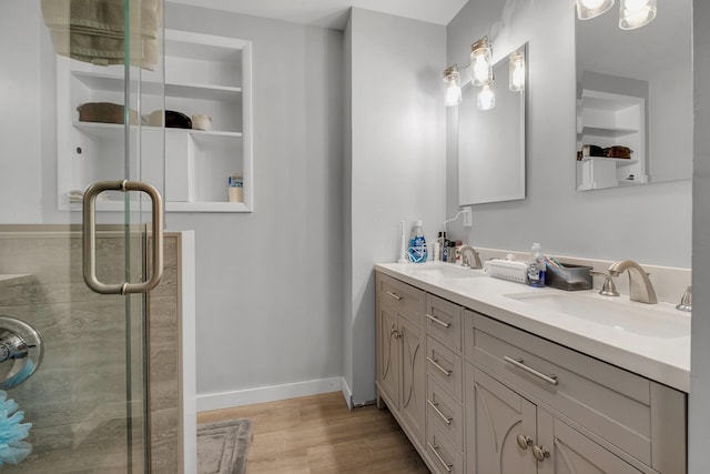 bathroom with double vanity, a stall shower, a sink, and wood finished floors