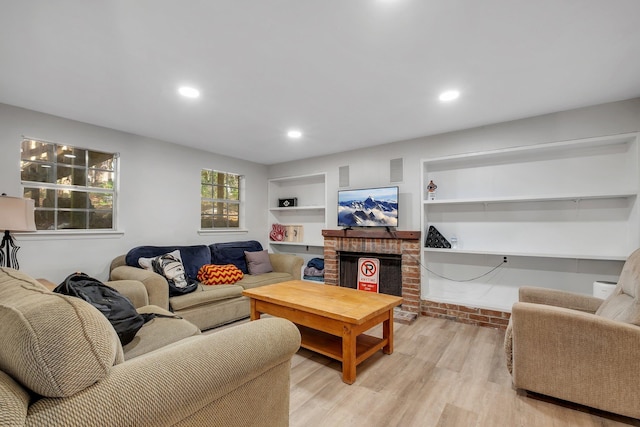 living room with built in features, recessed lighting, a fireplace, and light wood finished floors