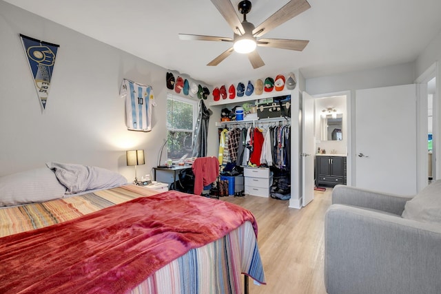 bedroom with light wood finished floors, a closet, a ceiling fan, a sink, and connected bathroom