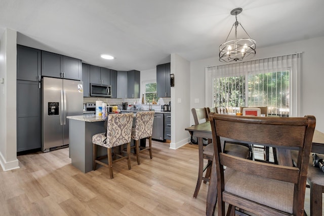 kitchen featuring appliances with stainless steel finishes, light wood-type flooring, a center island, and decorative backsplash