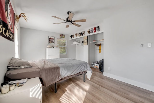 bedroom featuring light wood-style flooring, baseboards, ceiling fan, and a closet