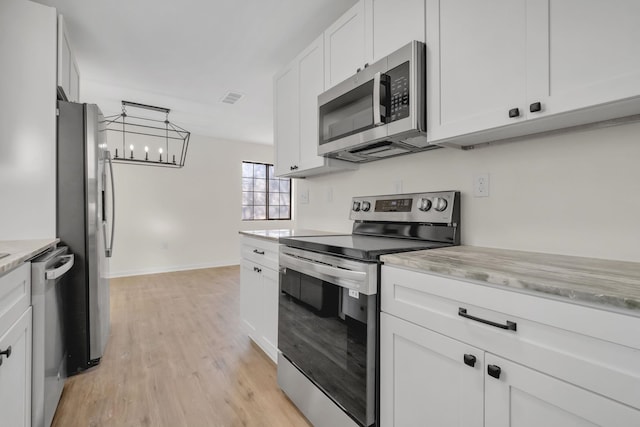 1115 Joe Louis St, Tallahassee, FL 32304 - kitchen with appliances with stainless steel finishes, light countertops, light wood-style floors, white cabinetry, and a chandelier