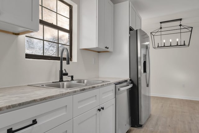 1115 Joe Louis St, Tallahassee, FL 32304 - kitchen with appliances with stainless steel finishes, white cabinetry, light wood-type flooring, and a chandelier