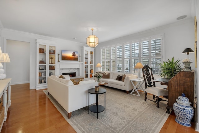 living room with crown molding, a high end fireplace, and light wood-type flooring