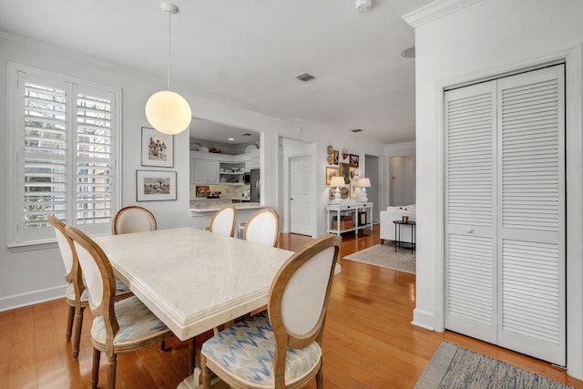 dining room featuring ornamental molding and light wood-type flooring