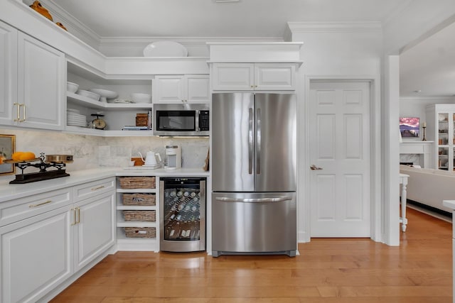 kitchen featuring white cabinetry, stainless steel appliances, beverage cooler, and decorative backsplash