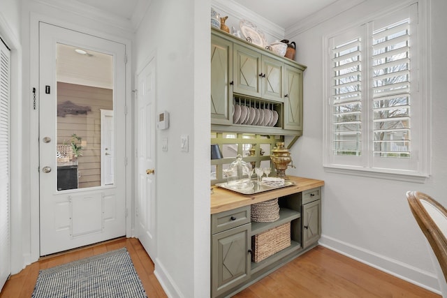 bar featuring crown molding, butcher block counters, light hardwood / wood-style floors, and green cabinetry