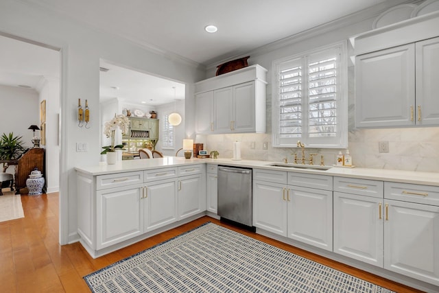 kitchen featuring sink, white cabinetry, light wood-type flooring, stainless steel dishwasher, and decorative backsplash