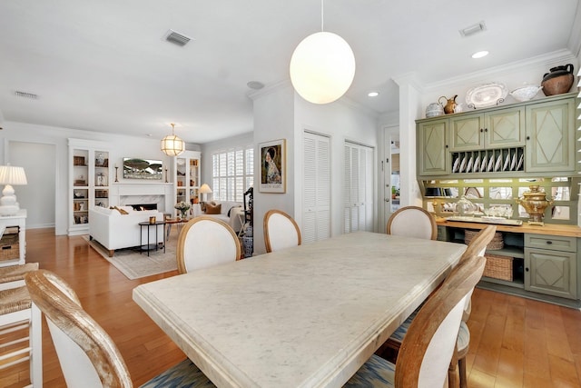 dining area featuring crown molding, light hardwood / wood-style floors, and a premium fireplace