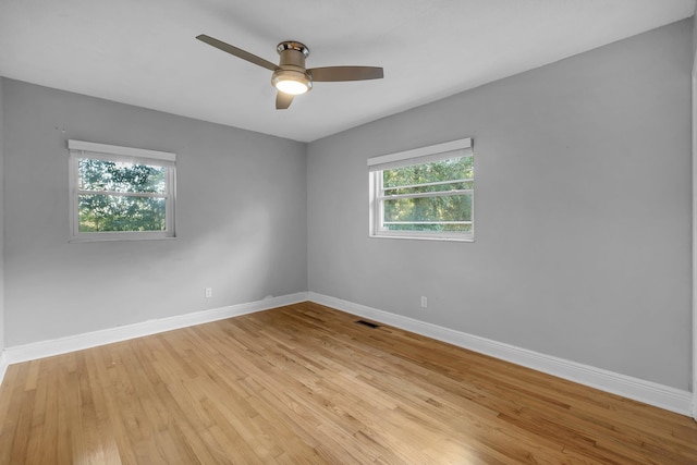 empty room with light hardwood / wood-style floors, a wealth of natural light, and ceiling fan