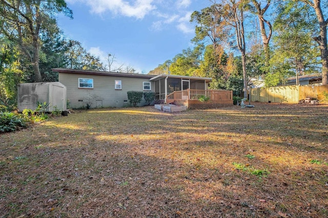 rear view of property featuring a sunroom, a storage shed, a yard, and a wooden deck