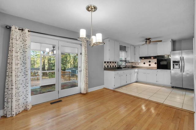 kitchen featuring sink, stainless steel fridge, oven, decorative backsplash, and ceiling fan with notable chandelier