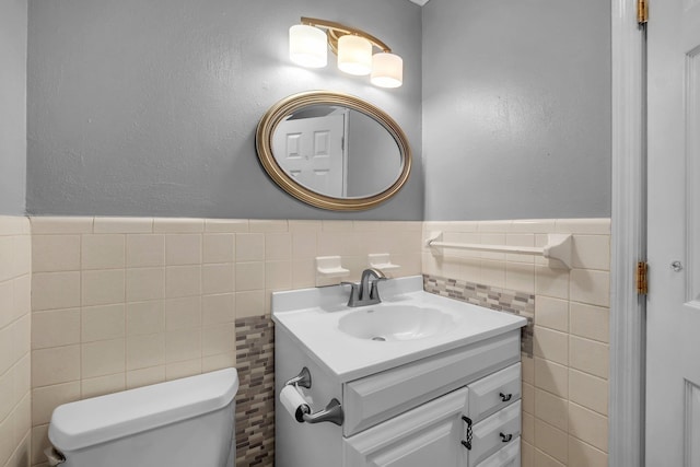 bathroom with vanity, toilet, and tile walls