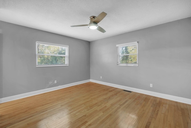 spare room featuring ceiling fan, a healthy amount of sunlight, light hardwood / wood-style floors, and a textured ceiling