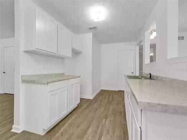 kitchen featuring light hardwood / wood-style floors, white cabinetry, and sink