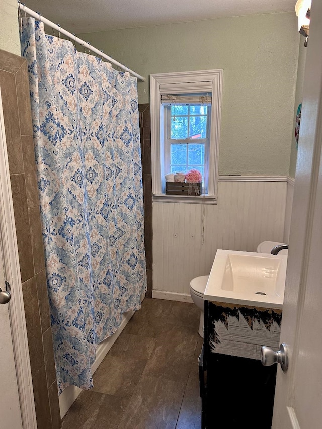 bathroom with a shower with shower curtain, vanity, toilet, and wood walls