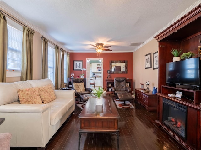 living room featuring dark wood-type flooring, a textured ceiling, ceiling fan, and ornamental molding