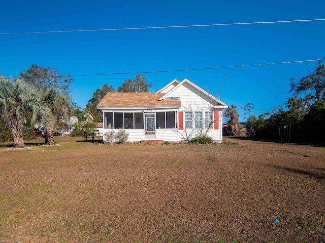 rear view of house featuring a yard and a sunroom