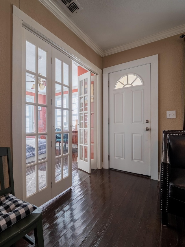 foyer featuring dark wood-type flooring, french doors, crown molding, and plenty of natural light