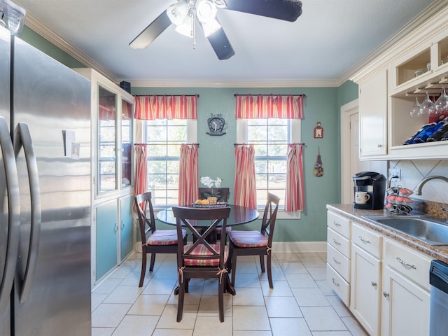 kitchen with ornamental molding, stainless steel fridge, white cabinets, and sink