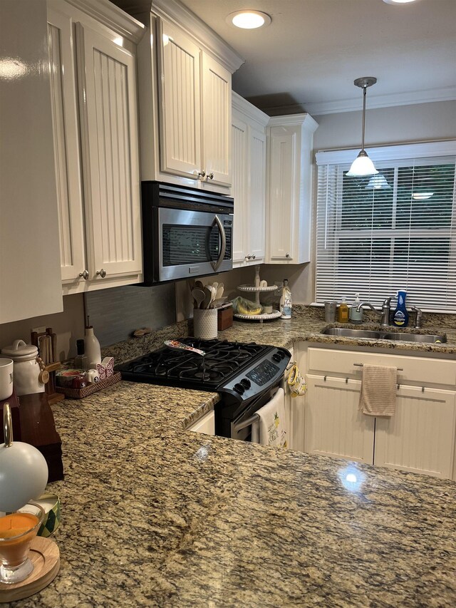 1045 Martin St, Tallahassee, FL 32303 - kitchen featuring stainless steel microwave, range with gas stovetop, white cabinets, crown molding, and dark stone counters