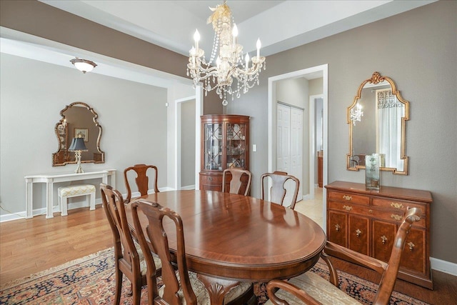 dining space with light hardwood / wood-style flooring and an inviting chandelier