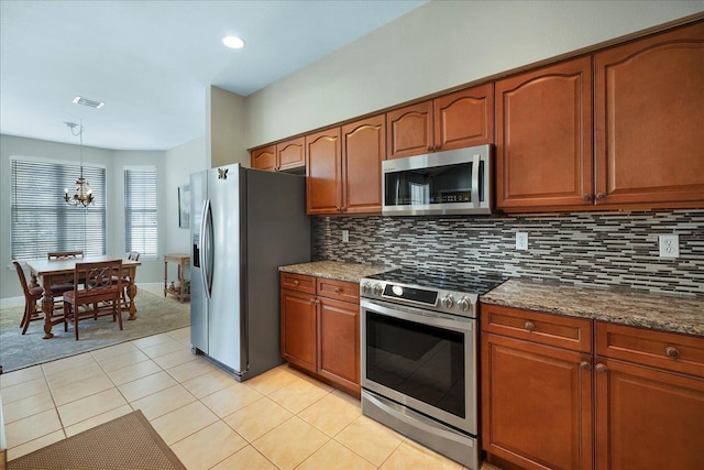 kitchen featuring dark stone counters, hanging light fixtures, stainless steel appliances, and decorative backsplash