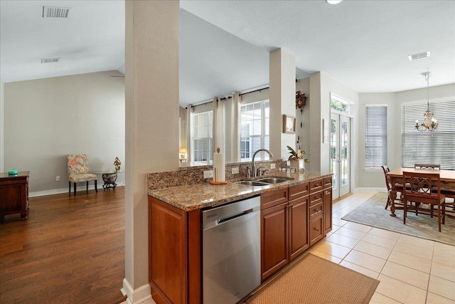 kitchen featuring decorative light fixtures, an inviting chandelier, sink, stainless steel dishwasher, and stone counters