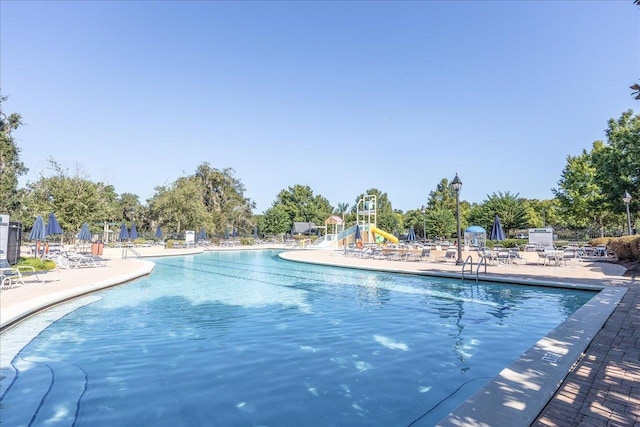 view of pool featuring a playground, a patio, and a water slide