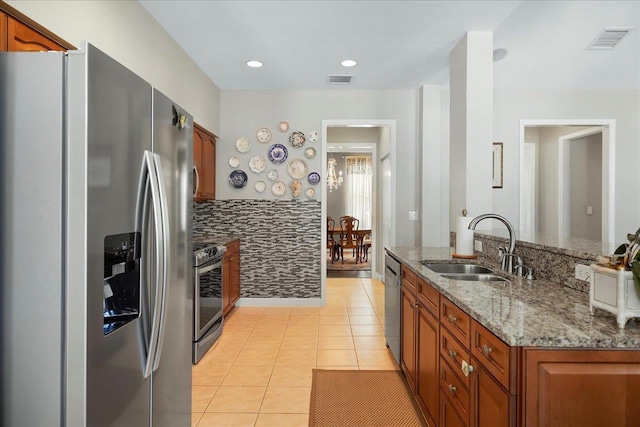 kitchen featuring light tile patterned flooring, sink, stainless steel appliances, and light stone countertops