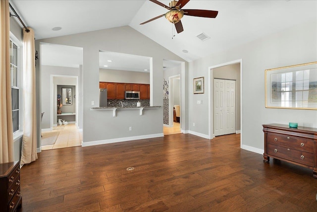 living room featuring ceiling fan, high vaulted ceiling, and dark wood-type flooring