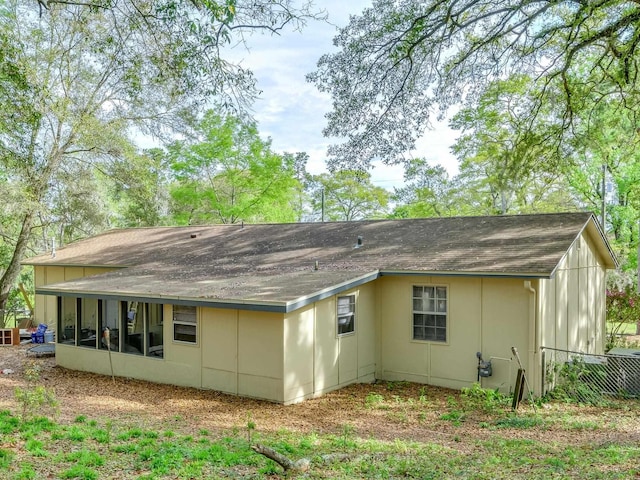 back of house featuring roof with shingles and a sunroom