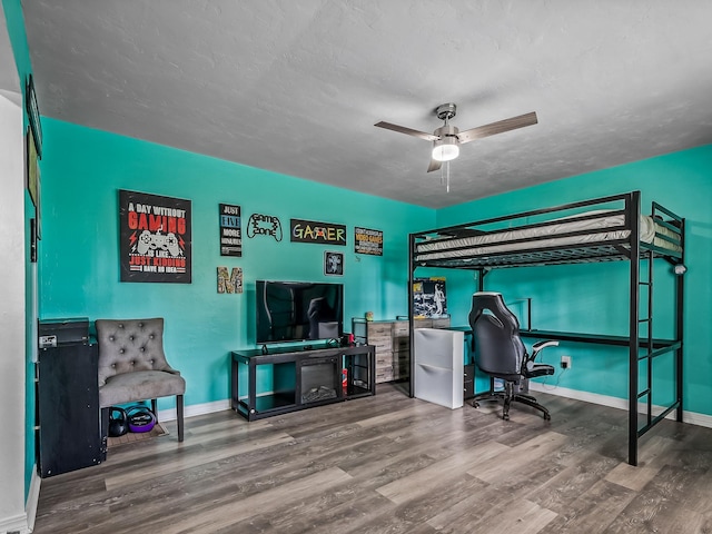 bedroom with baseboards, a textured ceiling, wood finished floors, and a ceiling fan