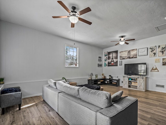 living room with wood finished floors, visible vents, and ceiling fan