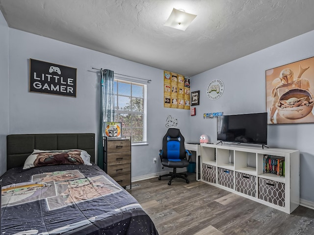 bedroom featuring baseboards, a textured ceiling, and wood finished floors