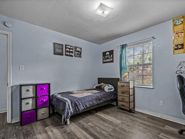 bedroom with a textured ceiling, baseboards, and wood finished floors