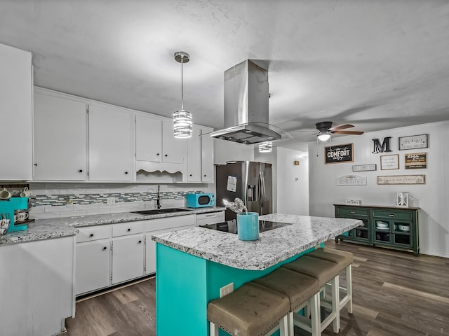 kitchen featuring dark wood finished floors, island exhaust hood, stainless steel refrigerator with ice dispenser, black electric cooktop, and a sink