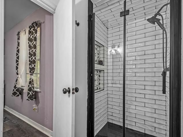 bathroom with tiled shower and baseboards