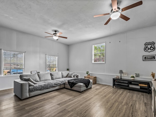 living area with a ceiling fan and wood finished floors