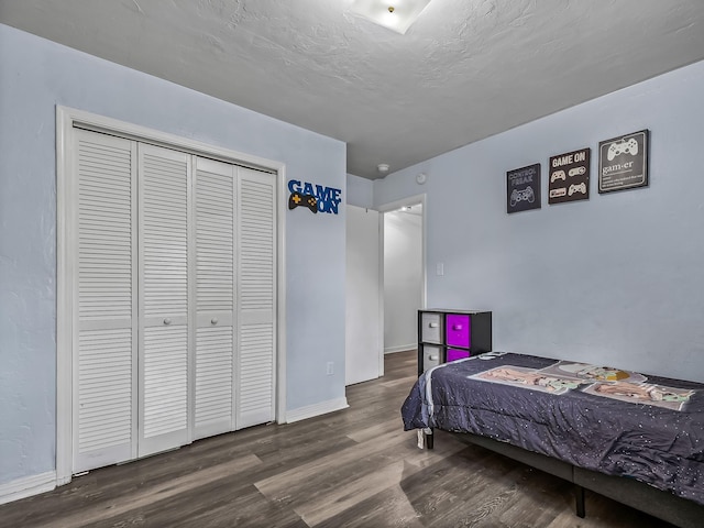 bedroom with a closet, a textured ceiling, baseboards, and wood finished floors