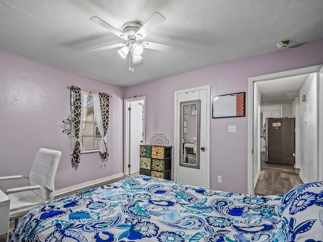 bedroom with a ceiling fan, freestanding refrigerator, baseboards, and wood finished floors