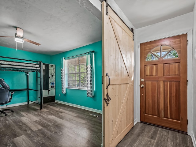 foyer entrance featuring baseboards, a ceiling fan, a barn door, and wood finished floors