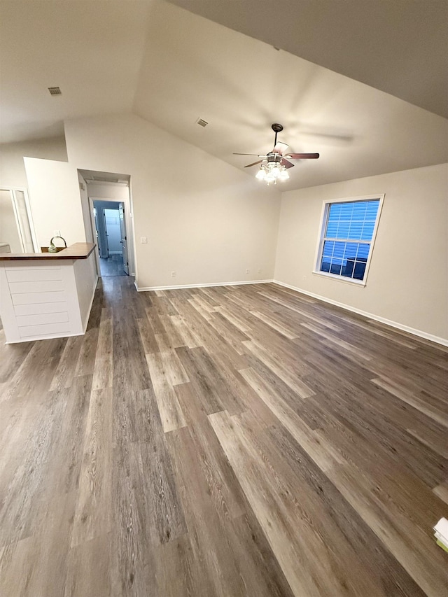 unfurnished living room with ceiling fan, vaulted ceiling, and dark hardwood / wood-style flooring