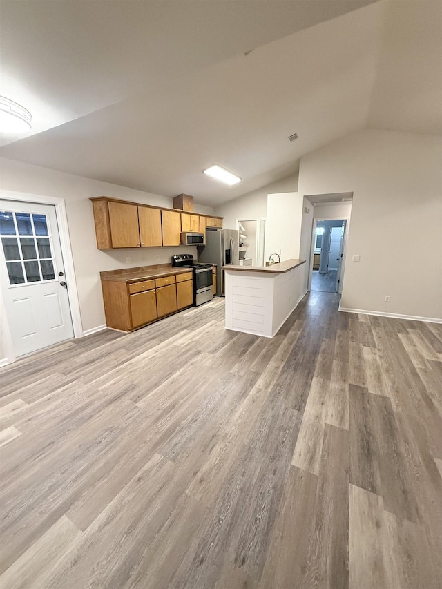 kitchen with lofted ceiling, sink, light hardwood / wood-style flooring, stainless steel appliances, and kitchen peninsula