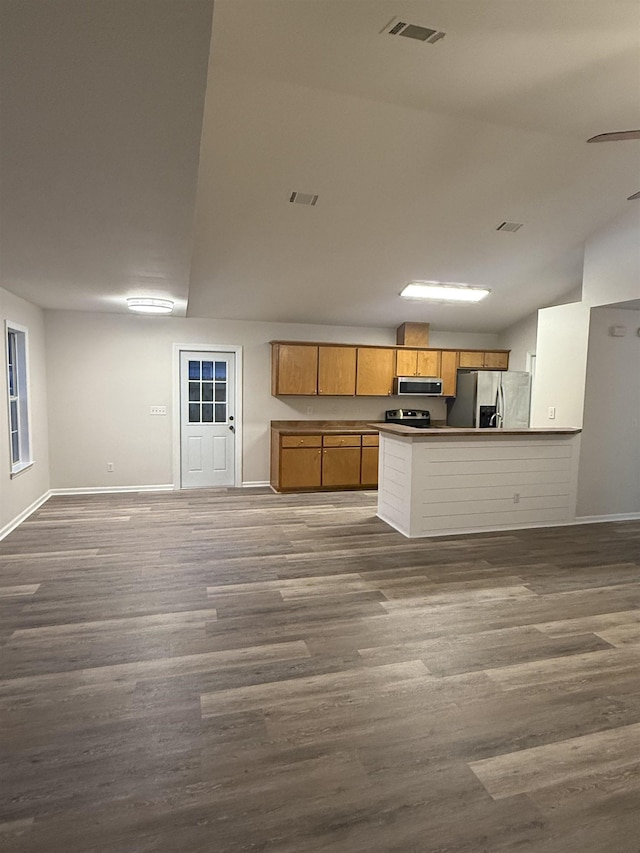 kitchen with appliances with stainless steel finishes, dark hardwood / wood-style floors, and kitchen peninsula