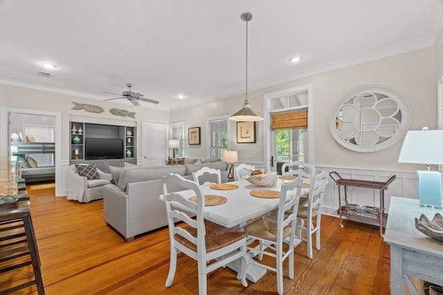 dining room with ceiling fan, wood-type flooring, and crown molding