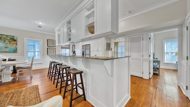 kitchen featuring white cabinetry, light hardwood / wood-style flooring, a healthy amount of sunlight, and stainless steel fridge