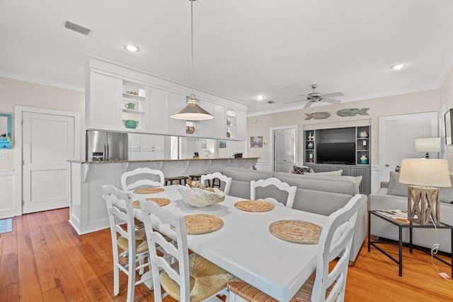 dining space featuring light hardwood / wood-style flooring, ceiling fan, and crown molding